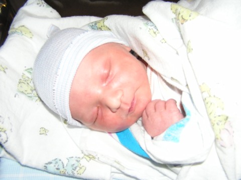 [Photo: The face of newborn Maxwell, sleeping cozily on his side]